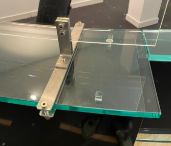 Infektionsschutzscheiben gebogen. Gefordert war eine spurlose Demontagemöglichkeit auf einer 19 mm starken Tresenscheibe aus Glas.